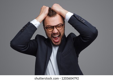 Adult bearded businessman in glasses pulling out hair and screaming with stress on gray background - Powered by Shutterstock