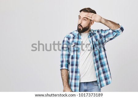 Adult bearded guy wiping his forehead with hand making phew gesture, expressing relief while standing against gray wall. Man feels happy that he prevented huge disaster. It was close enough