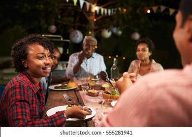 Adult Black Family Eat Dinner In Garden, Over Shoulder View