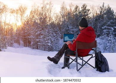 Adult blogger or freelancer working on a laptop at winter nature. Man working outdoors. Concept remote work.