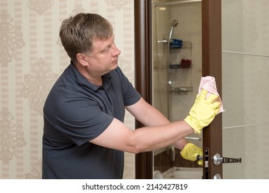 An Adult Blond Man Washes The Bathroom Door.