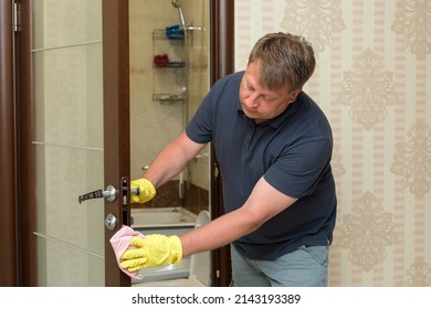 An Adult Blond Man Washes Bathroom Door.