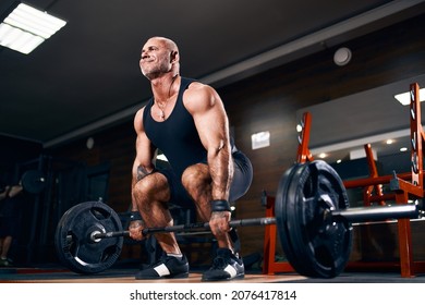Adult Bodybuilder Muscular Man Doing Heavy Deadlift Exercise with weight while in gym in dark. Bodybuilding concept .