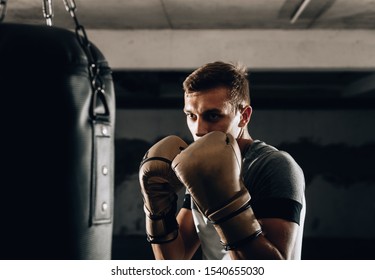 Adult boxer in boxing gloves training with boxing punching bag in a gym - Powered by Shutterstock