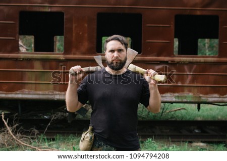 Image, Stock Photo bearded man huntsman with two axes stands near a rusty train