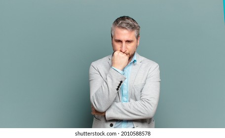 adult businessman feeling serious, thoughtful and concerned, staring sideways with hand pressed against chin