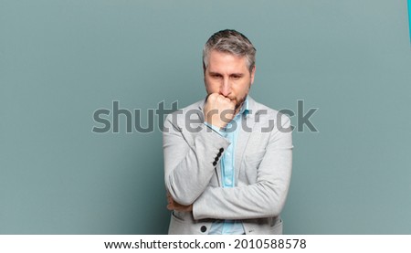 adult businessman feeling serious, thoughtful and concerned, staring sideways with hand pressed against chin