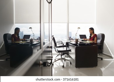 Adult Businesswoman Sitting In Modern Office In Skyscraper. The Secretary Is Concentrated And Writes Email On Tablet Computer. Wide Shot