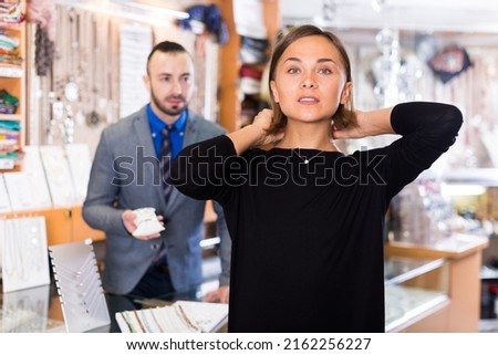 Adult buyer woman choosing chainlet and pendants in the jewelry store.