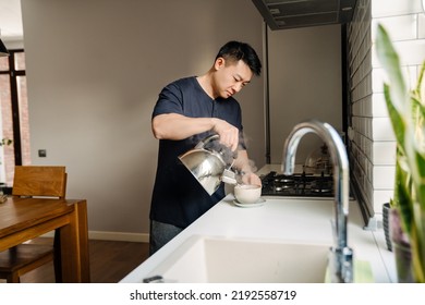 Adult Calm Asian Man Making Tea In Cozy Kitchen At Home