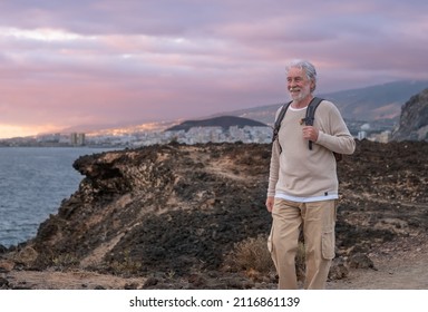 Adult caucasian gray haired senior man walking in countryside close to the sea wearing backpack looking at the horizon enjoying nature. Freedom and vacation concept. Cloudy sky. Copy space - Powered by Shutterstock