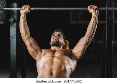 Adult Caucasian Male Doing Bench Presses With Weights In A Dark Gymnasium