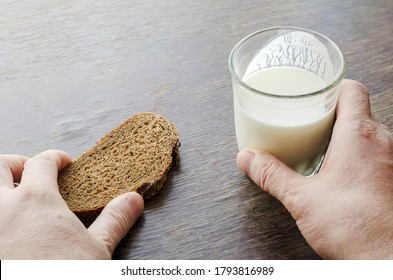 Adult Caucasian Male Eating Kefir With Rye Bread. One Hand Holds Half-empty Glass Of Kefir. Another Slice Of Rye Bread. Simple Healthy Food. Top View At An Angle.