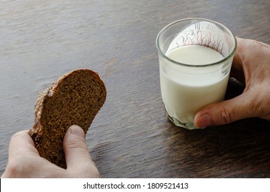 Adult Caucasian Male Eating Kefir With Rye Bread. One Hand Holds Half-empty Glass Of Kefir. Another Slice Of Rye Bread. Simple Healthy Food. Top View At An Angle.
