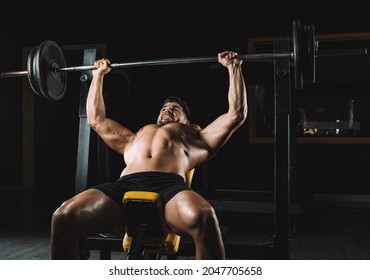 Adult Caucasian Male Shirtless Doing Bench Presses With Weights In A Bar In A Dark Gymnasium