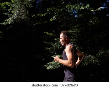 Adult Caucasian man running in forest in summer