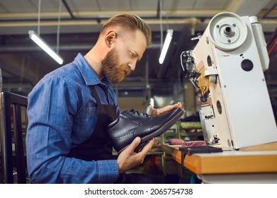 Adult caucasian man shoemaker in uniform holding handmade leather boot checking for defects. Craftsman in apron working at workplace. Shoe factory, footwear industry and cobbler shop concept - Powered by Shutterstock