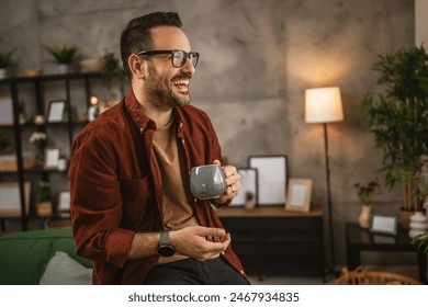 Adult caucasian man sit and hold coffee look out the window at home and smile - Powered by Shutterstock