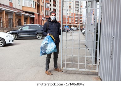 Adult Caucasian Man Wearing Medical Mask Taking Out The Garbage To Trash Enclosure Of Residential House