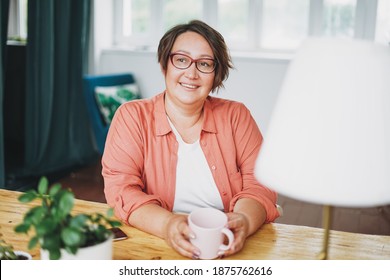 Adult charming brunette woman in glasses plus size body positive with cup of tea at home - Powered by Shutterstock