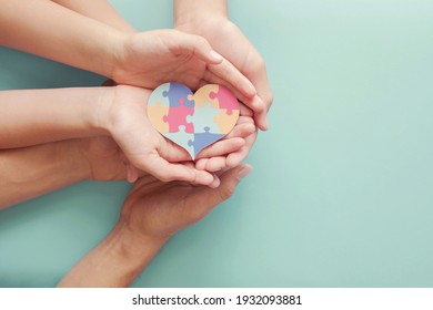 Adult and chiildren hands holding jigsaw puzzle heart shape, Autism awareness,Autism spectrum disorder family support concept, World Autism Awareness Day