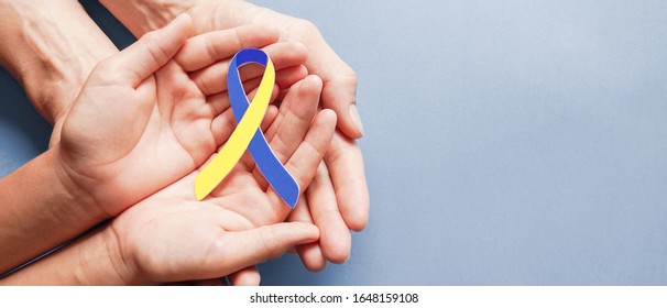 Adult and child hands holding blue and yellow ribbon shaped paper, Down syndrome awareness , World down syndrome day - Powered by Shutterstock