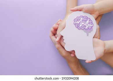Adult and child hands holding encephalography brain paper cutout,autism, Stroke, Epilepsy and alzheimer awareness, seizure disorder, stroke, ADHD, world mental health day concept - Shutterstock ID 1932094208