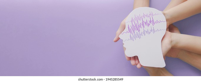 Adult and child hands holding encephalography brain paper cutout, autism, Epilepsy awareness, seizure disorder, stroke, alzheimer, mental health concept - Shutterstock ID 1945285549