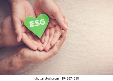 Adult And Child Hands Holding Green Heart With ESG, Environmental, Social And Corporate Governance Concept