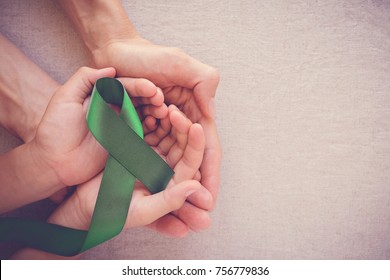adult and child hands holding Green Ribbon, cancer awareness, Liver, Gallbladder Bile Duct cancer awareness, Hepatitis B awareness, world mental health day, organ donation