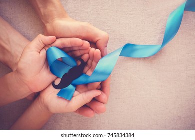 Adult And Child Hands Holding Light Blue Ribbons With Mustache , Prostate Cancer Awareness, Men Health Awareness, International Men's Day