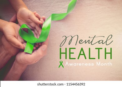 Adult and child hands holding Lime GreenRibbon, Mental health awareness month - Shutterstock ID 1154456392