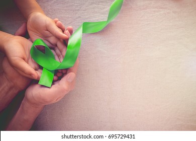 Adult And Child Hands Holding Lime Green Ribbon, Children Mental Health Awareness And Organ Donation, World Mental Health Day, World Kidney Day