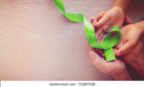 Adult And Child Hands Holding Lime Green Ribbon, Panoramic Banner Background, Mental Health Awareness And Organ Donation, World Mental Health Day, World Kidney Day