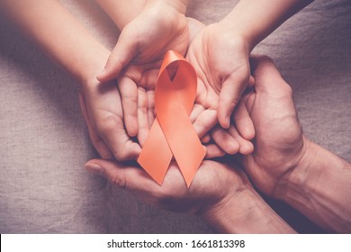 Adult And Child Hands Holding Orange Ribbons,  Leukemia Cancer And Multiple Sclerosis, COPD And ADHD Awareness, World Kidney Day