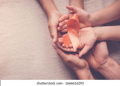 Adult And Child Hands Holding Orange Ribbons,  Leukemia Cancer And Multiple Sclerosis, COPD And ADHD Awareness, World Kidney Day