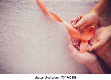 Adult And Child Hands Holding Orange Ribbons,  Leukemia Cancer Awareness And Multiple Sclerosis Awareness, COPD And ADHD Awareness, World Kidney Day