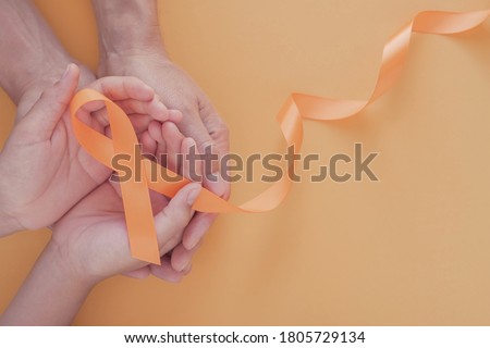 Adult and child hands holding orange Ribbons,  Leukemia cancer and Multiple sclerosis, COPD and ADHD awareness, world kidney day
