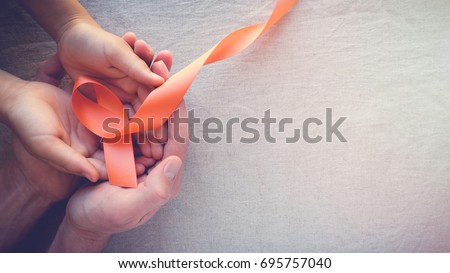 Adult and child hands holding orange Ribbons,  Leukemia cancer awareness and Multiple sclerosis awareness, COPD and ADHD awareness, world kidney day