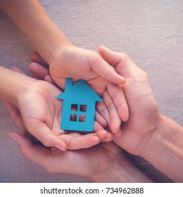 Adult And Child Hands Holding Paper House, Family Home, Homeless Shelter And Real Estate Concept