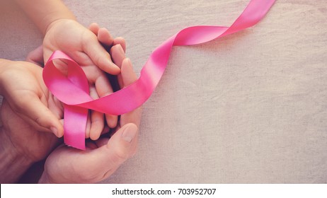 Adult and child hands holding pink ribbons, Breast cancer awareness, abdominal cancer awareness and October Pink day panoramic background , world cancer day