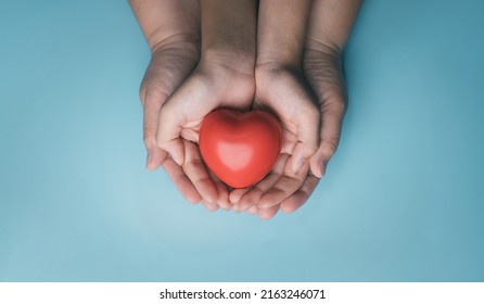 Adult And Child Hands Holding Red Heart On Aqua Background, Heart Health, Donation, CSR, Hope,wellbeing, World Heart Day, World Health Day, Family Day, Fair Trade, Organ Donor Day, Foster Home Concept