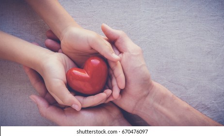 adult and child hands holding red heart, health care, love and family insurance concept, world heart day
