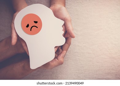 Adult and child hands holding sad face in brain paper cutout, unhappy hormones, imbalance brain chemicals, negative mental health concept - Shutterstock ID 2139490049