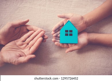 Adult And Child Hands Holding White House, Family Home And Homeless Shelter Concept