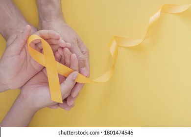 Adult And Child Hands Holding Yellow Gold Ribbon, Sarcoma Awareness, Bone Cancer, Childhood Cancer Awareness, World Suicide Prevention Day, September Yellow

