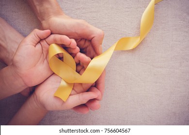 adult and child hands holding yellow gold ribbon, Sarcoma Awareness, Bone cancer, childhood cancer awareness, World Suicide Prevention Day, September yellow