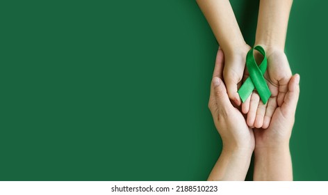 Adult and child hands holds green ribbon on green background. World lymphoma awareness day. September 15. Liver, Gallbladders bile duct, kidney Cancer and Lymphoma Awareness month. Banner. copy space - Shutterstock ID 2188510223
