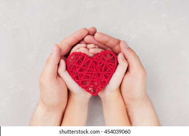 Adult And Child Holding Red Heart In Hands Top View. Happy Family Relationships, Health Care, Pediatric Cardiology Concept.