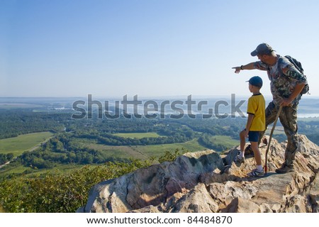 Adult and child standing on a mountaintop near the Arkansas River. The father shows his son the sights